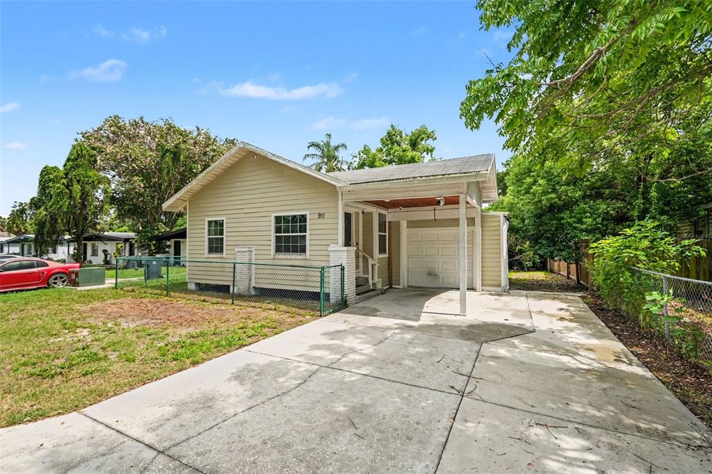 A single-story house with light-colored siding, a front carport, and a concrete driveway — 911 E 123RD AVENUE, TAMPA, FL