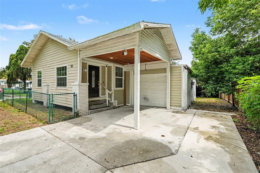 A single-story house with light siding, a front porch, and an attached garage — 911 E 123RD AVENUE, TAMPA, FL