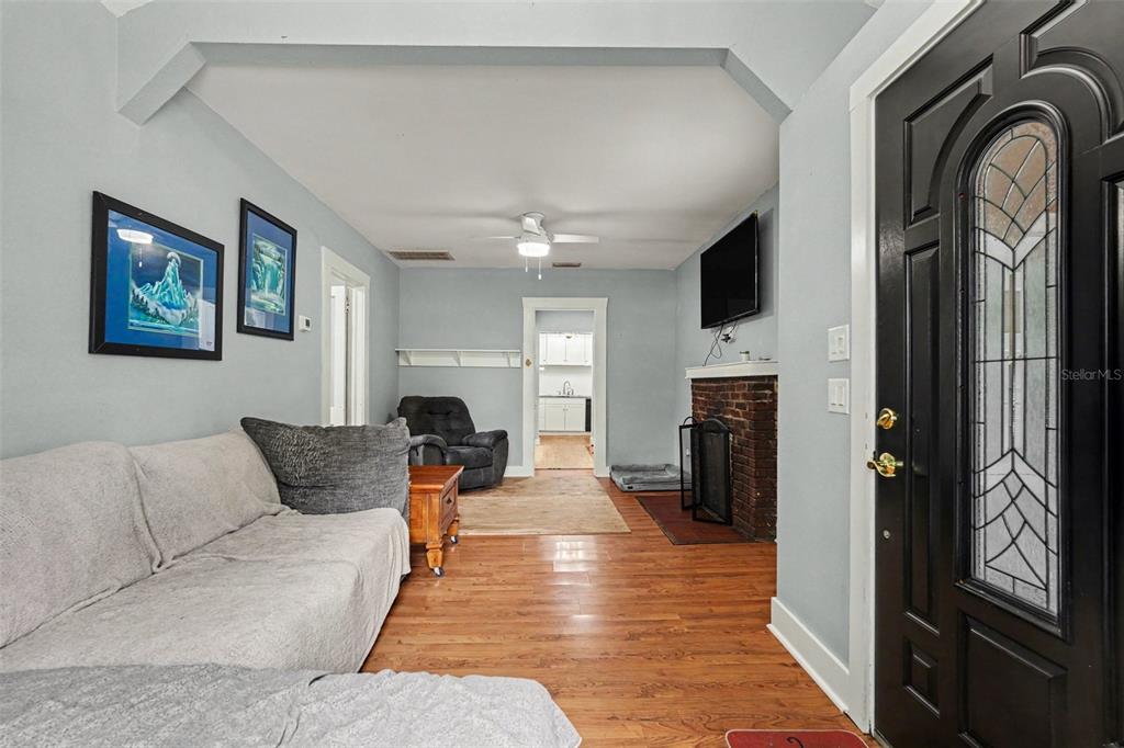 A living room features light blue walls, hardwood floors, a brick fireplace, and a front door — 911 E 123RD AVENUE, TAMPA, FL