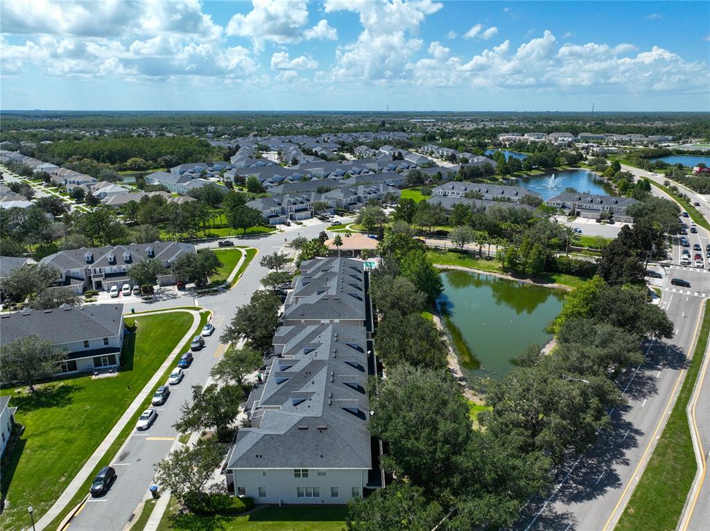 An aerial view shows a multi-unit residential building with gray roofs near a small pond — 14061 TURNING LEAF DRIVE, ORLANDO, FL