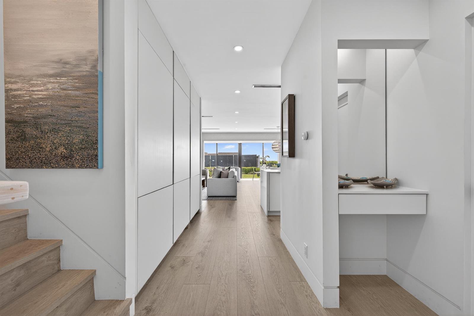 A hallway with light wood floors leads past a built-in vanity toward a bright living area — 5720 Old Ocean Boulevard # 5e, Ocean Ridge FL 33435, OCEAN RIDGE, FL