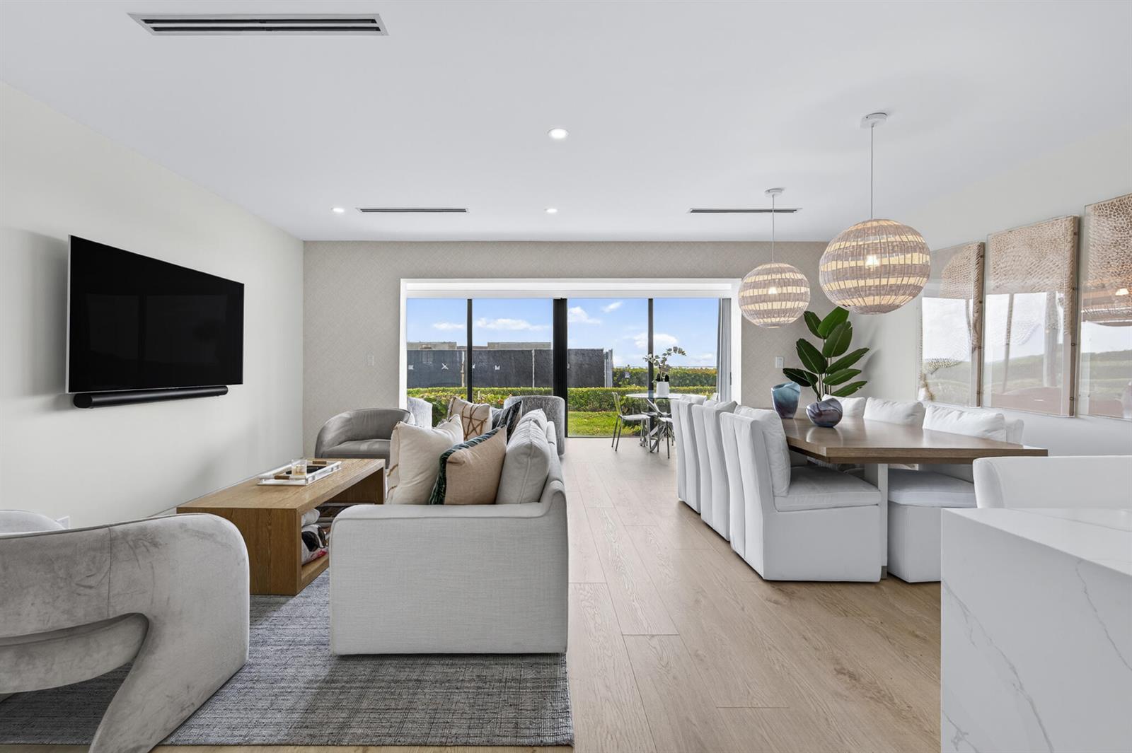 A bright open-plan living and dining area features light wood floors and large sliding doors — 5720 Old Ocean Boulevard # 5e, Ocean Ridge FL 33435, OCEAN RIDGE, FL
