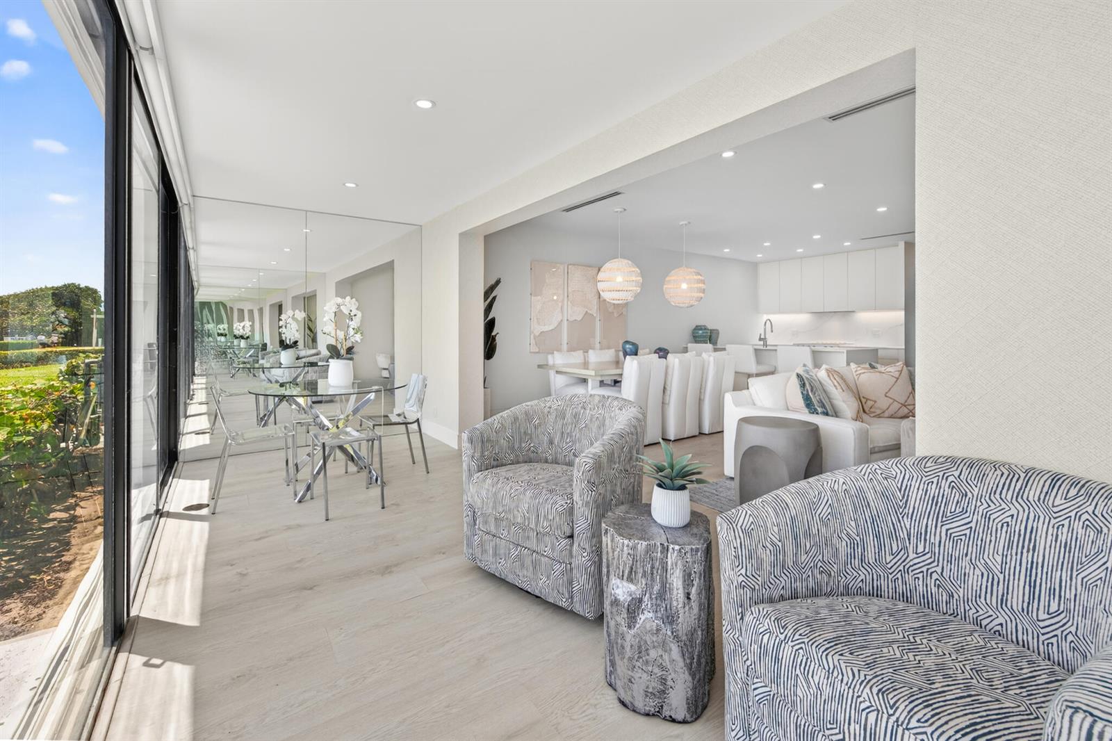 A bright living and dining area features patterned armchairs, light wood flooring, and floor-to-ceiling windows — 5720 Old Ocean Boulevard # 5e, Ocean Ridge FL 33435, OCEAN RIDGE, FL