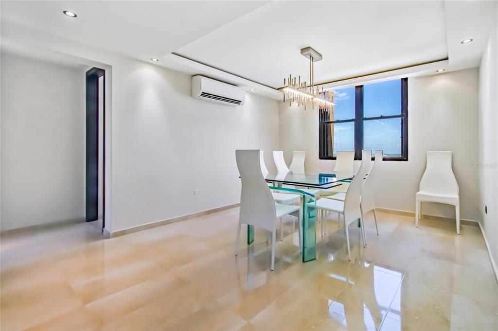 A dining room features a glass table, white chairs, a modern chandelier, and tiled floors — 1715 COND. LA INMACULADA PLAZA I UNIT PH4, SAN JUAN, PR