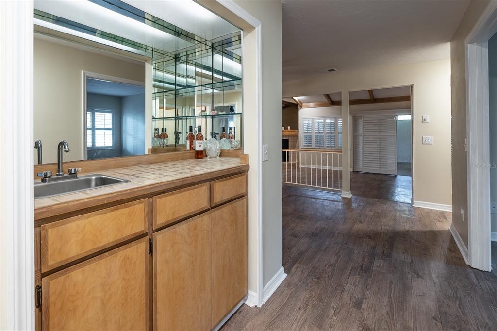 A wet bar with tile countertops and a mirrored backsplash sits beside a hallway entrance — 1720 NE 38 AVENUE, OCALA, FL