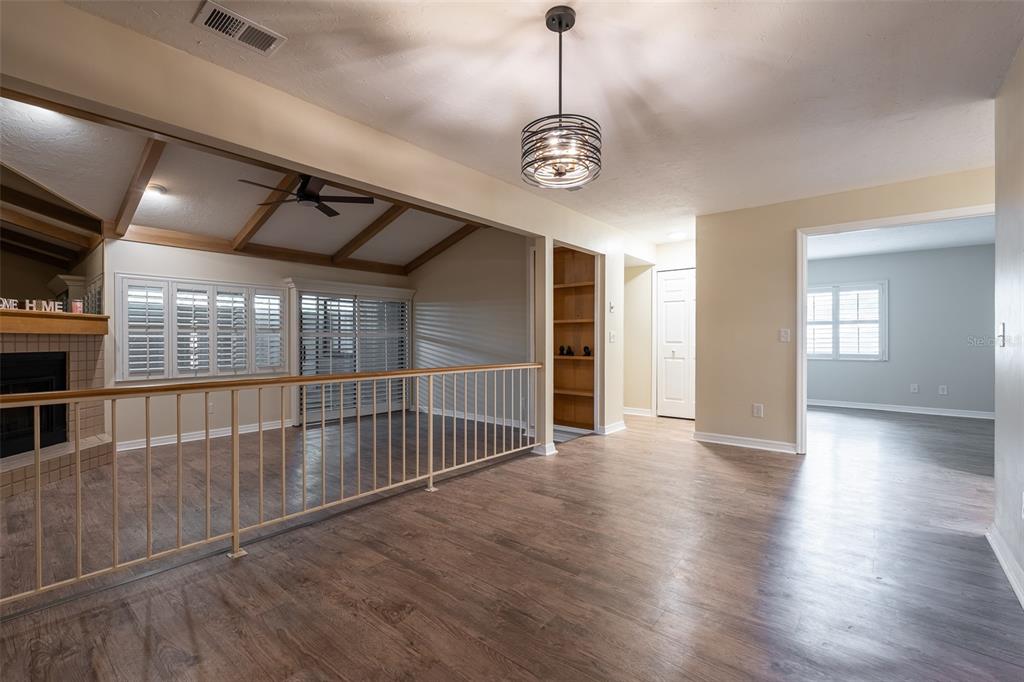 A living area with wood-look flooring, a metal railing, and a vaulted ceiling with beams — 1720 NE 38 AVENUE, OCALA, FL
