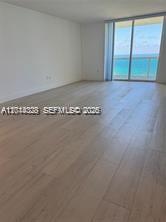 An empty room with light wood flooring and a sliding glass door overlooking the ocean — 10275 Collins Ave # 1435, Bal Harbour FL 33154, BAL HARBOUR, FL