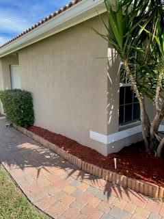 The exterior of a beige stucco house features a brick paver walkway and red mulch — 6655 Duval Avenue, West Palm Beach FL 33411, WEST PALM BEACH, FL