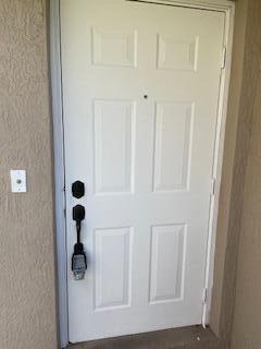 A white six-panel front door with a black handle set and a peephole — 6655 Duval Avenue, West Palm Beach FL 33411, WEST PALM BEACH, FL