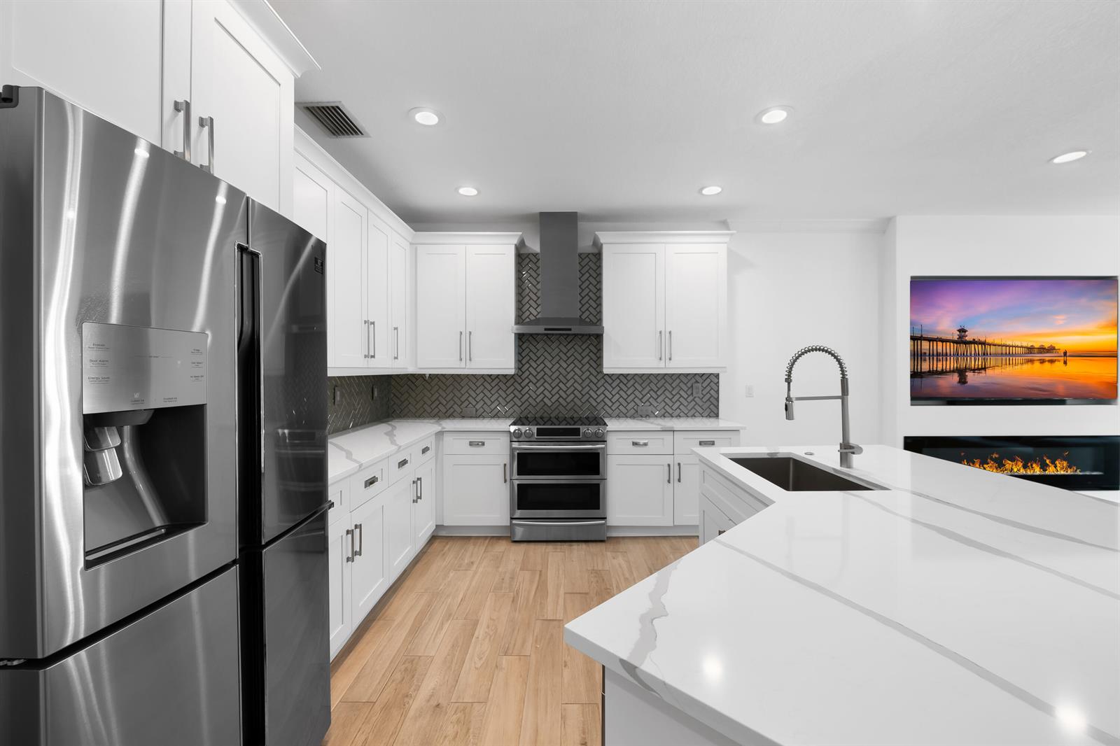 A modern kitchen features white cabinets, stainless steel appliances, a marble island, and herringbone backsplash — 10560 Walnut Valley Drive, Boynton Beach FL 33473, BOYNTON BEACH, FL