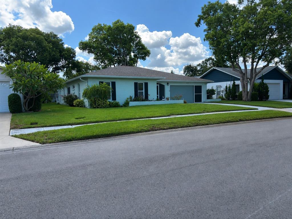 A light green single-story house with a garage and a manicured lawn — 11214 ROLLINGWOOD DRIVE, PORT RICHEY, FL