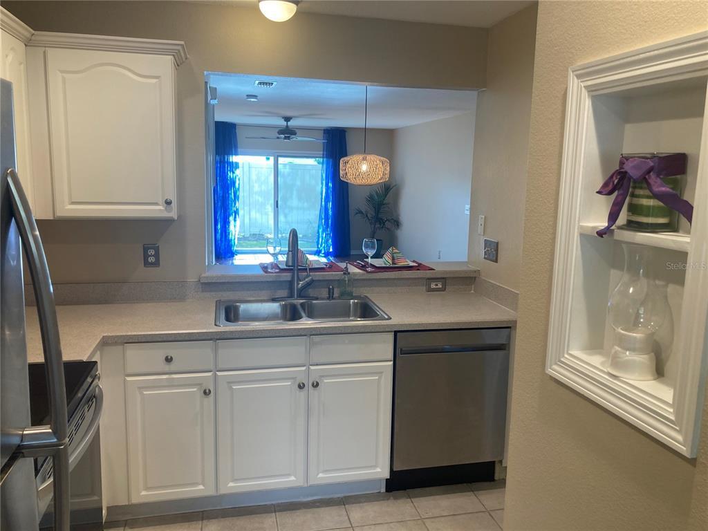 A kitchen features white cabinets, stainless steel appliances, a double sink, and a pass-through window — 2533 HARN BOULEVARD UNIT 2, CLEARWATER, FL