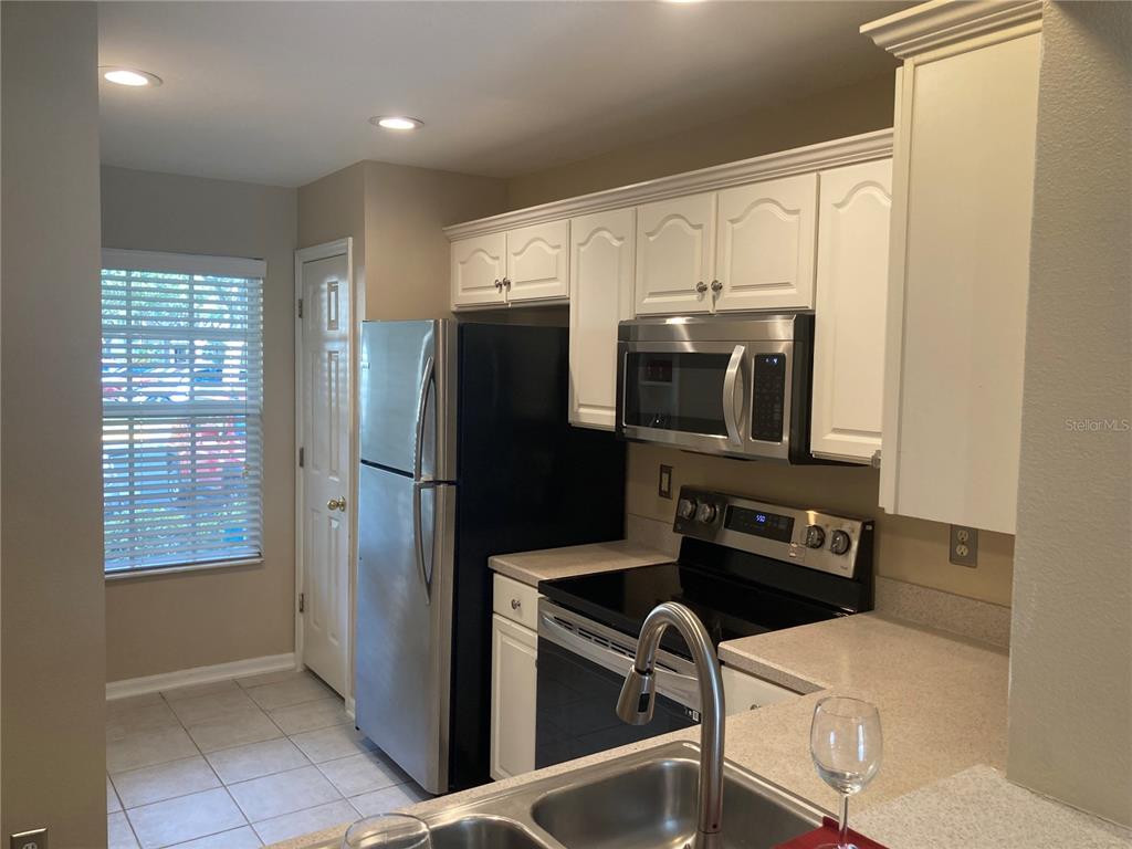 A kitchen features white cabinets, stainless steel appliances, a double sink, and tile flooring — 2533 HARN BOULEVARD UNIT 2, CLEARWATER, FL