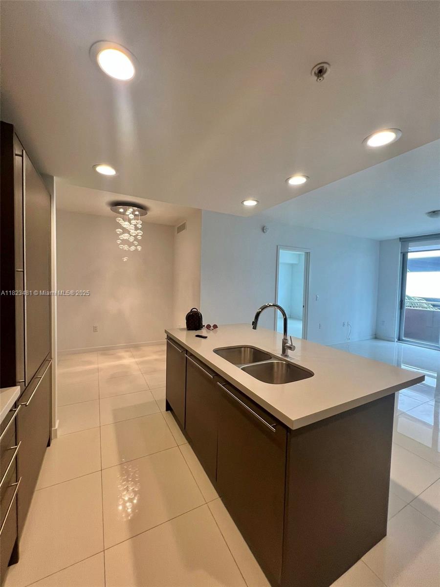 A modern kitchen features dark cabinetry, a white island countertop, and recessed ceiling lighting — 7661 NW 107th Ave # 207, Doral FL 33178, DORAL, FL