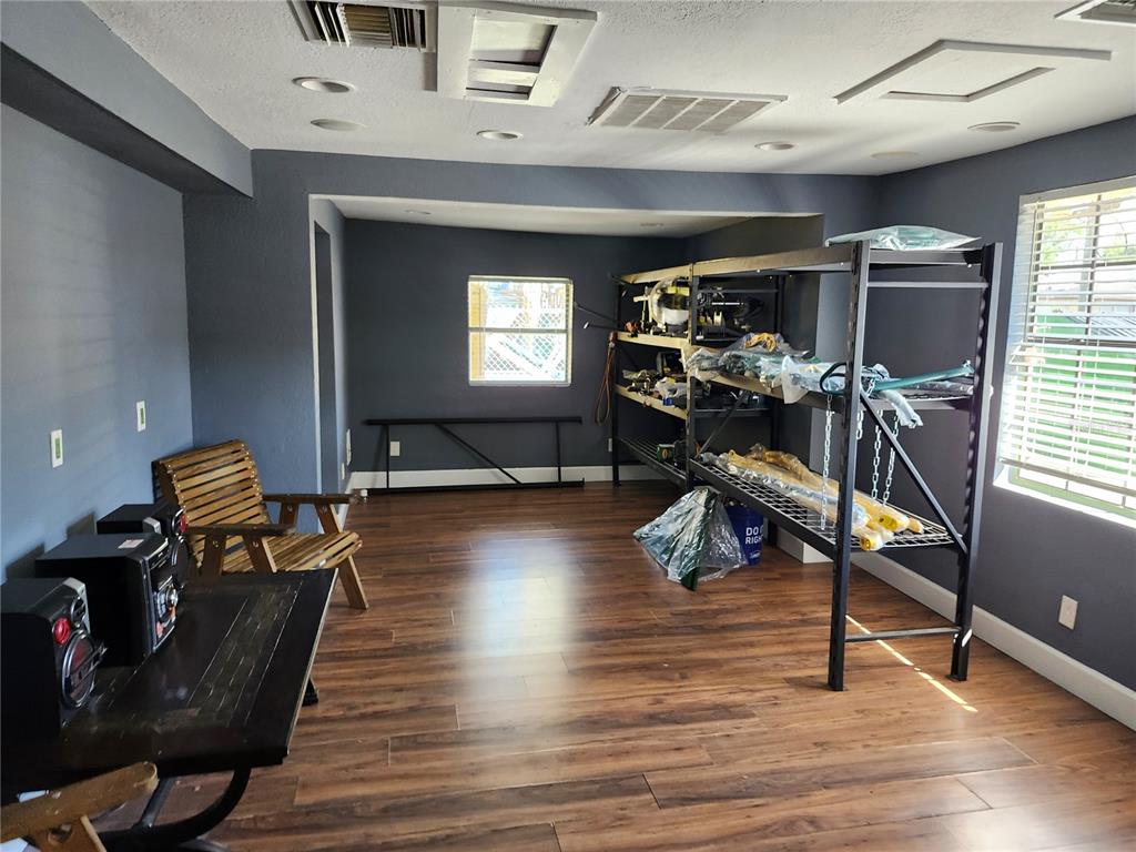 A room with gray walls, wood-look flooring, a metal storage rack, and a wooden chair — 1901 W SLIGH AVENUE, TAMPA, FL