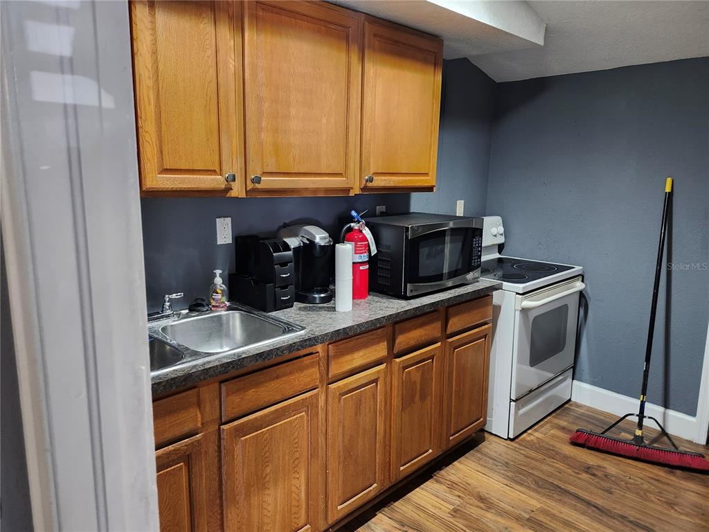 A kitchen features wood cabinets, a stainless steel sink, a microwave, and a white stove — 1901 W SLIGH AVENUE, TAMPA, FL