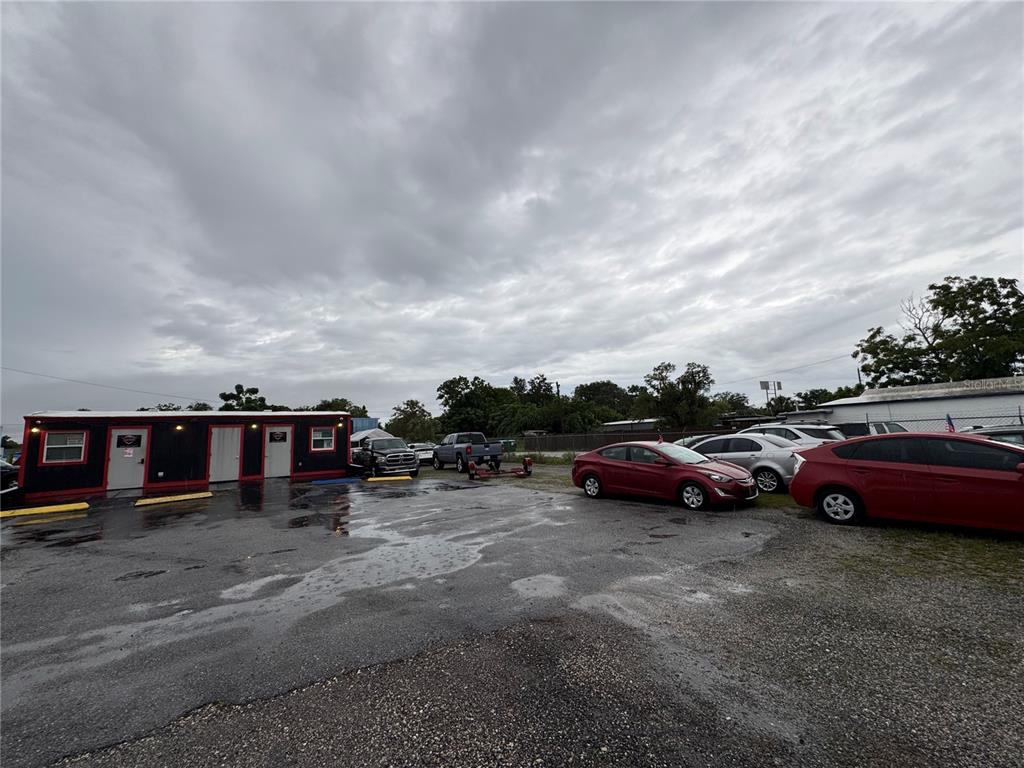 An exterior view of a small commercial building with a gravel parking lot and cars — 575 N US HIGHWAY 17 92, LONGWOOD, FL
