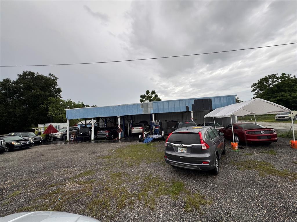 An exterior view of a commercial auto repair shop with multiple vehicles parked on gravel — 575 N US HIGHWAY 17 92, LONGWOOD, FL