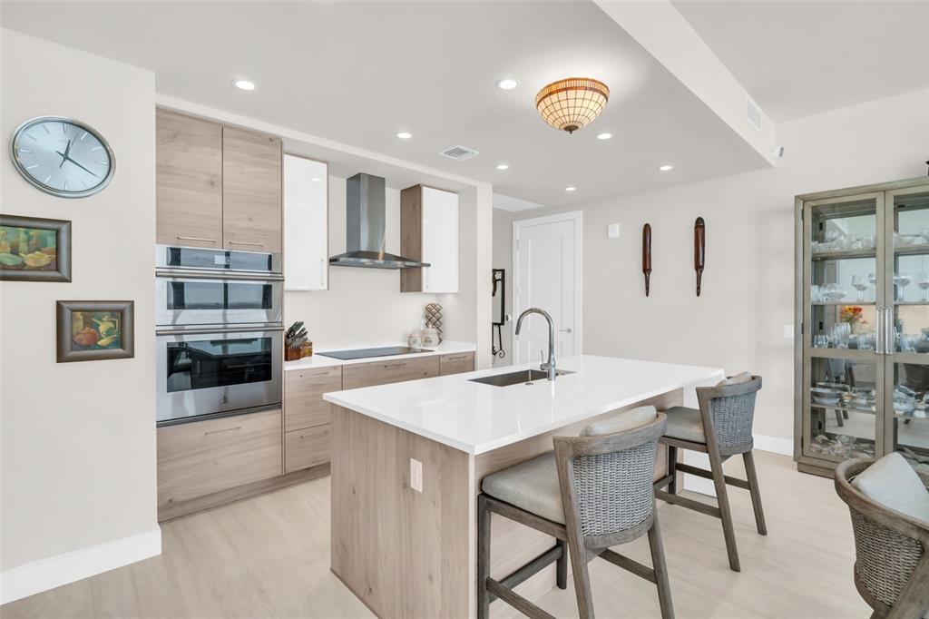 A modern kitchen features light wood cabinetry, a white quartz island, and stainless steel appliances — 301 1ST STREET S UNIT 3305, ST PETERSBURG, FL
