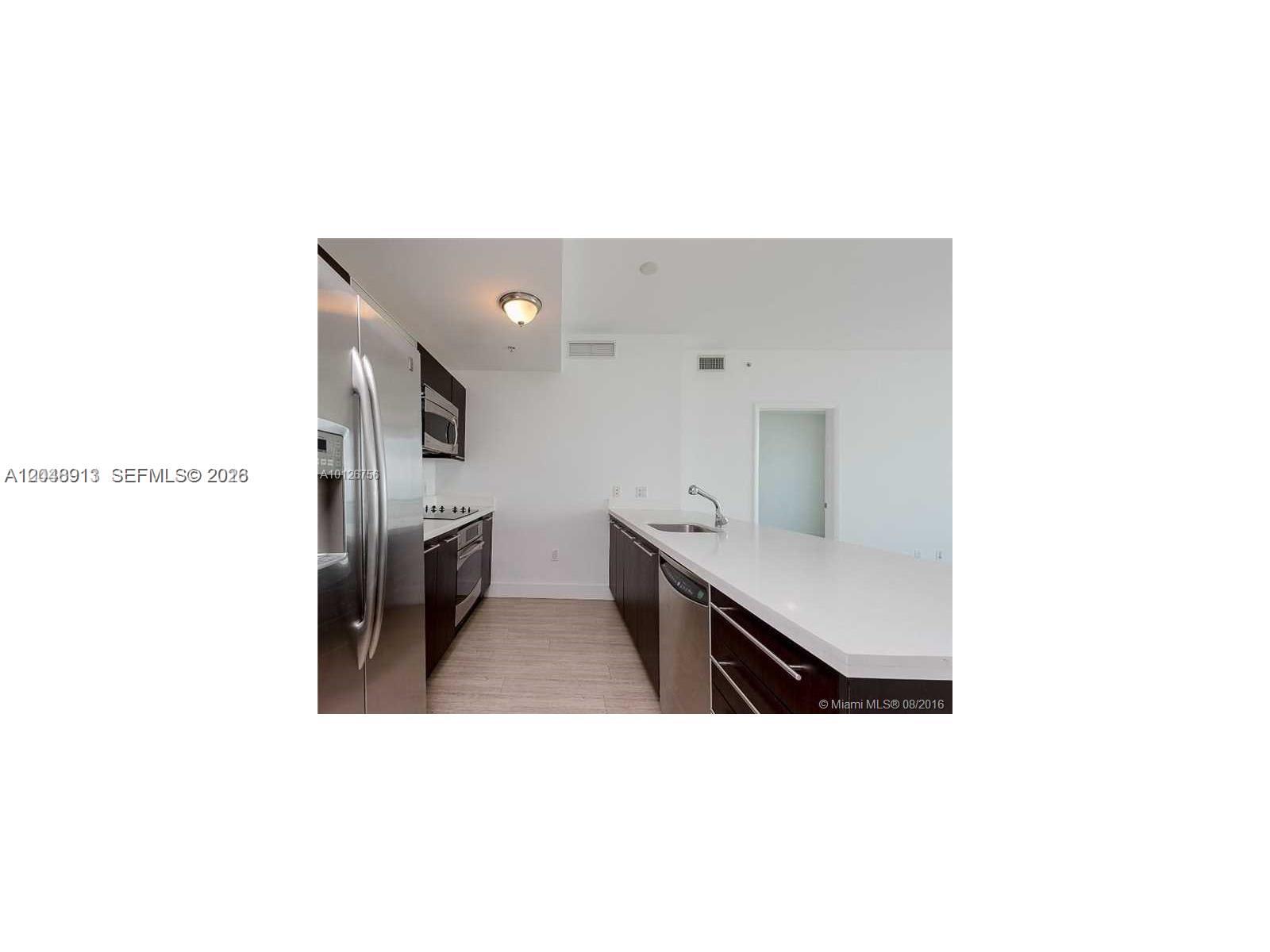 A modern kitchen features dark wood cabinets, stainless steel appliances, and a white countertop island — 90 SW 3rd St # 2609, Miami FL 33130, MIAMI, FL