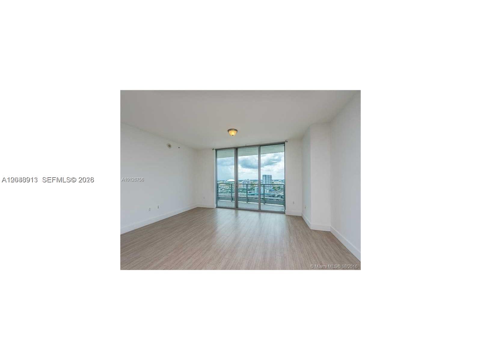 An empty room features light wood-look flooring, white walls, and a sliding glass door balcony — 90 SW 3rd St # 2609, Miami FL 33130, MIAMI, FL