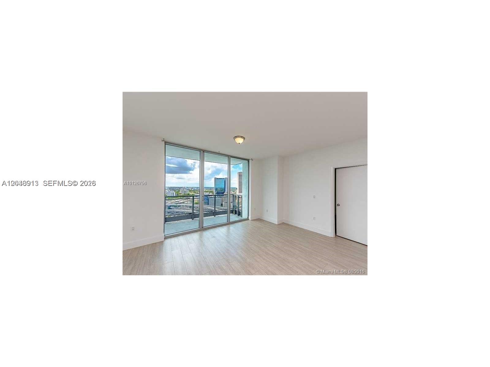 An empty room features light wood-look flooring, white walls, and a balcony with city views — 90 SW 3rd St # 2609, Miami FL 33130, MIAMI, FL