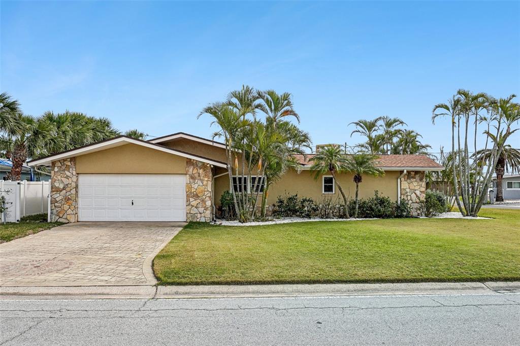 A single-story house with a stone-accented facade, a two-car garage, and palm trees — 5815 BALI WAY S, ST PETE BEACH, FL