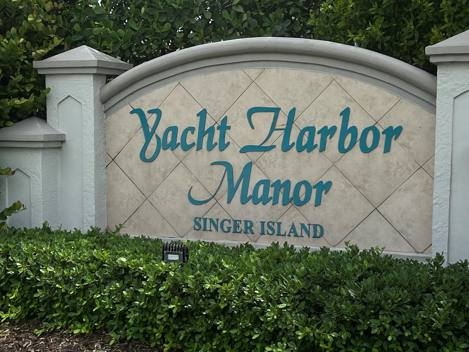 A stone monument sign for Yacht Harbor Manor on Singer Island sits behind green bushes — 1260 Manor Drive, Riviera Beach FL 33404, RIVIERA BEACH, FL