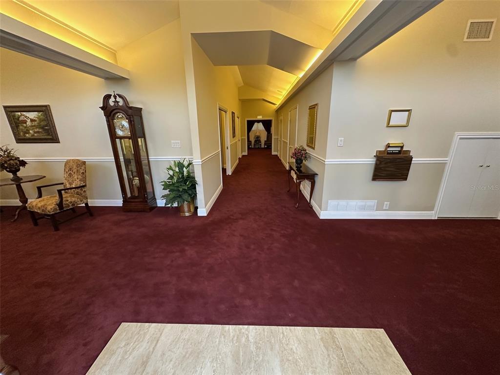 A wide hallway with red carpeting leads to a doorway under a vaulted ceiling — 500 E AIRPORT BOULEVARD, SANFORD, FL