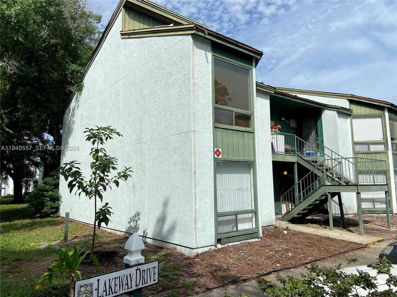 A two-story apartment building with light-colored stucco walls and green trim features exterior stairs — 4318 Lakeway Dr # D, Orlando FL 32839, ORLANDO, FL