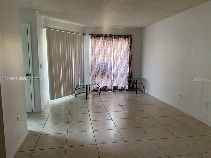 A living room with light-colored tile floors, white walls, and a sliding glass door — 4318 Lakeway Dr # D, Orlando FL 32839, ORLANDO, FL
