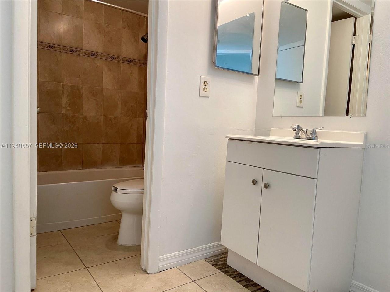 A bathroom features a white vanity, a mirror, and a tiled shower-tub combination — 4318 Lakeway Dr # D, Orlando FL 32839, ORLANDO, FL