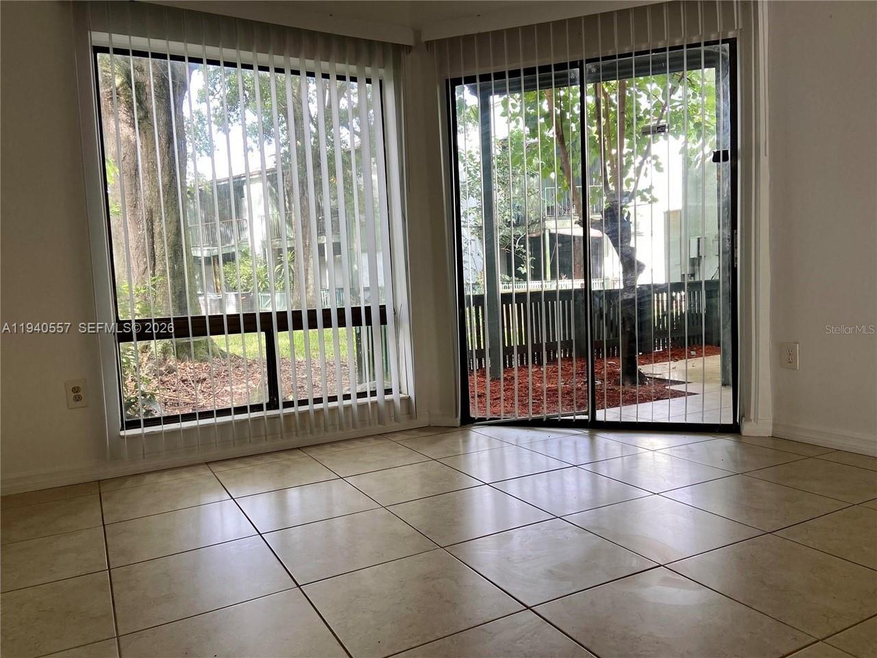 A room with beige tile flooring, vertical blinds, and a sliding glass door to a patio — 4318 Lakeway Dr # D, Orlando FL 32839, ORLANDO, FL
