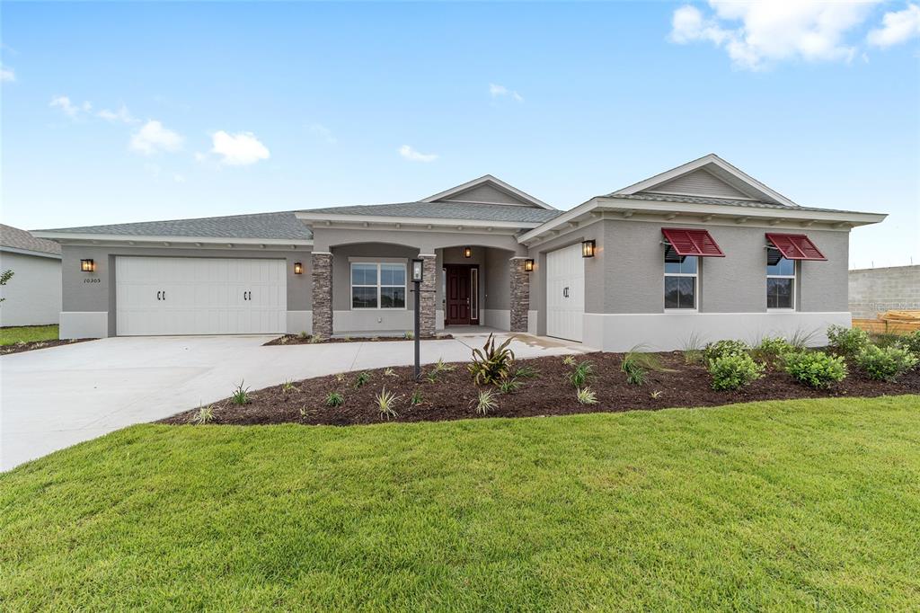 A single-story house with a gray stucco exterior, stone accents, and a two-car garage — 10305 SW 105TH TERRACE, OCALA, FL