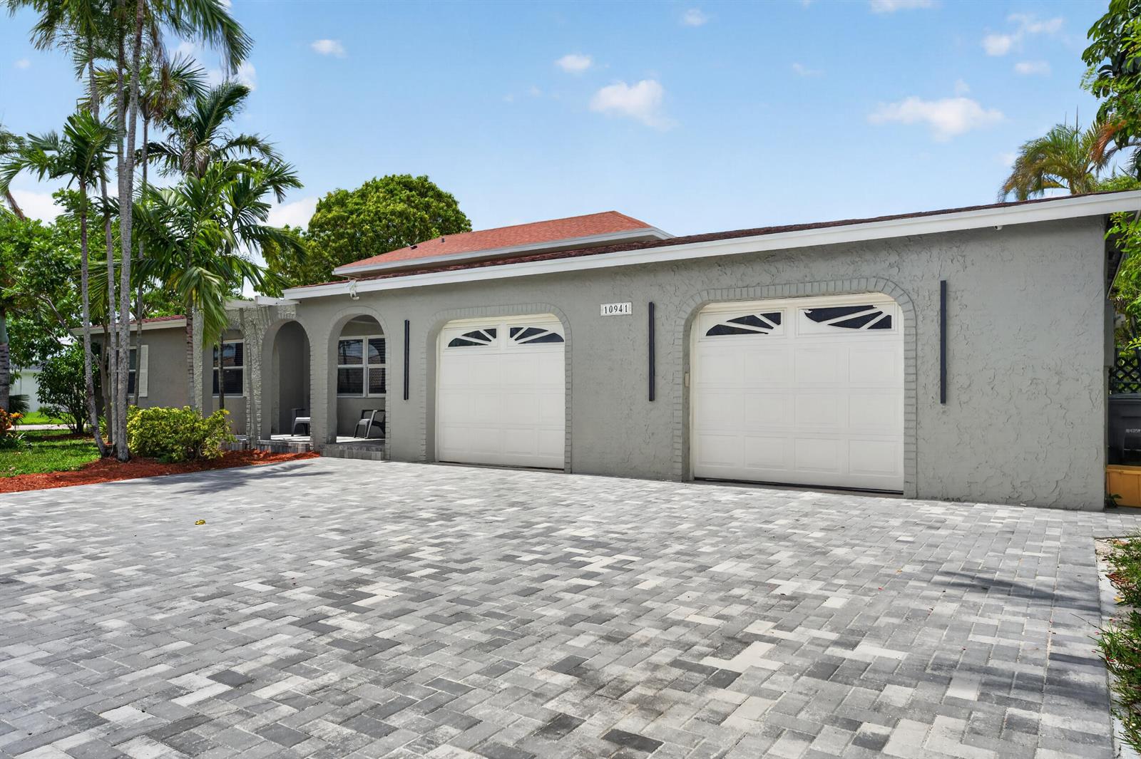 A gray house with a two-car garage and a paved driveway under a blue sky — 10941 Granite Street, Boca Raton FL 33428, BOCA RATON, FL