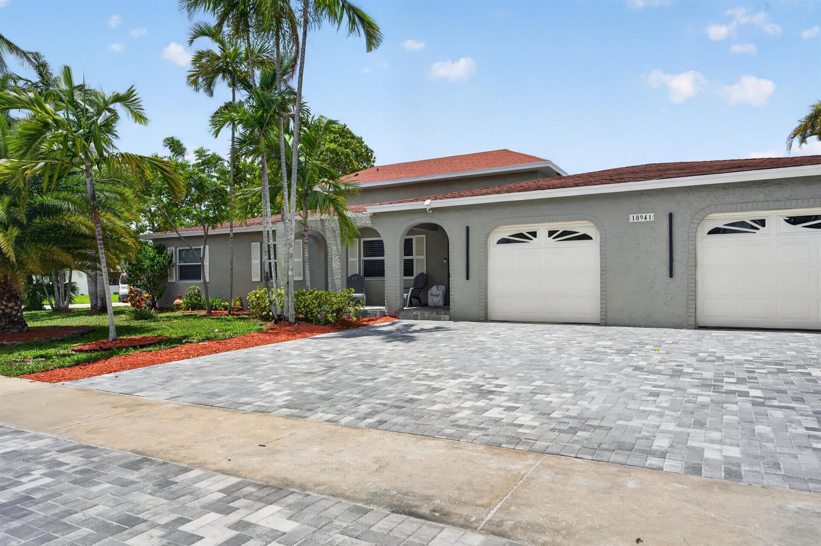 A gray single-story house features a paved driveway, two garage doors, and palm trees — 10941 Granite Street, Boca Raton FL 33428, BOCA RATON, FL