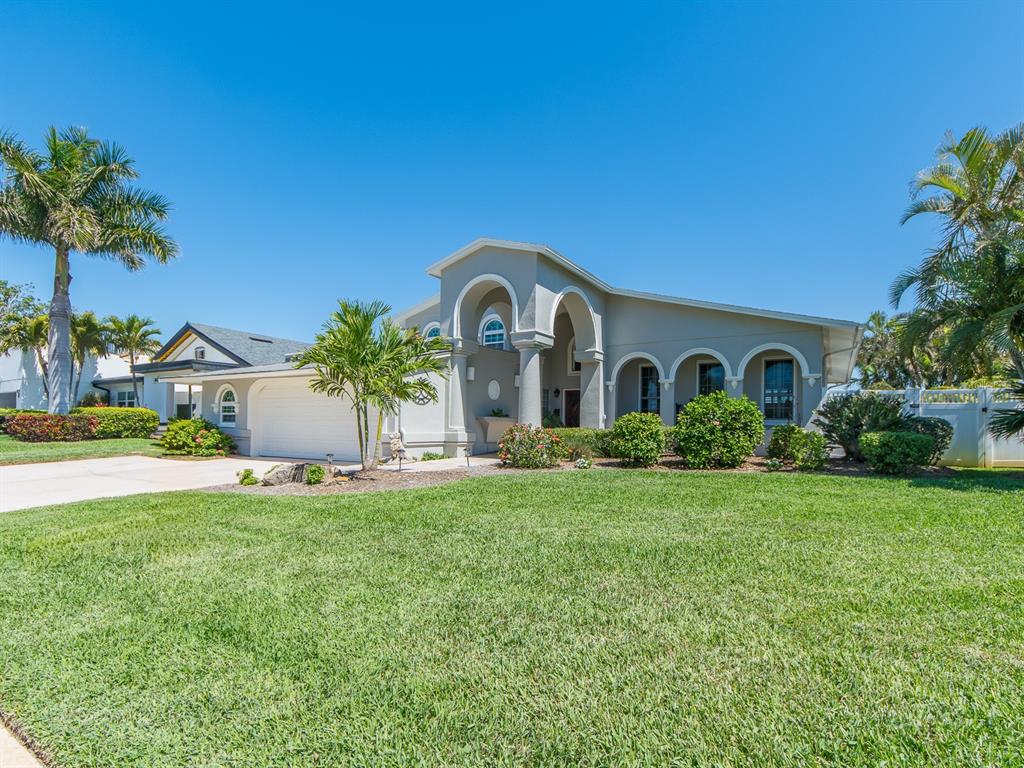 A single-story house with a white garage, arched entry, and palm trees on a lawn — 707 SNUG ISLAND, CLEARWATER BEACH, FL