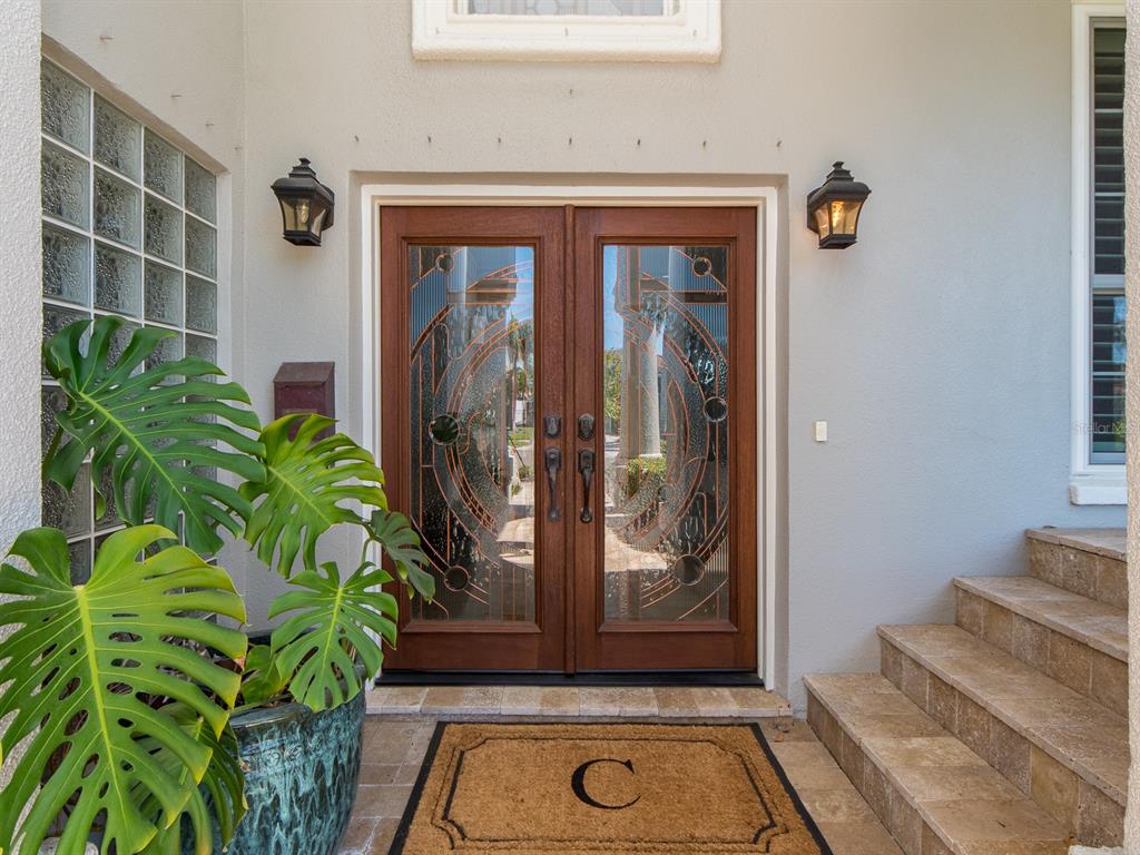 A front entryway features double wooden doors with decorative glass panels and a stone staircase — 707 SNUG ISLAND, CLEARWATER BEACH, FL