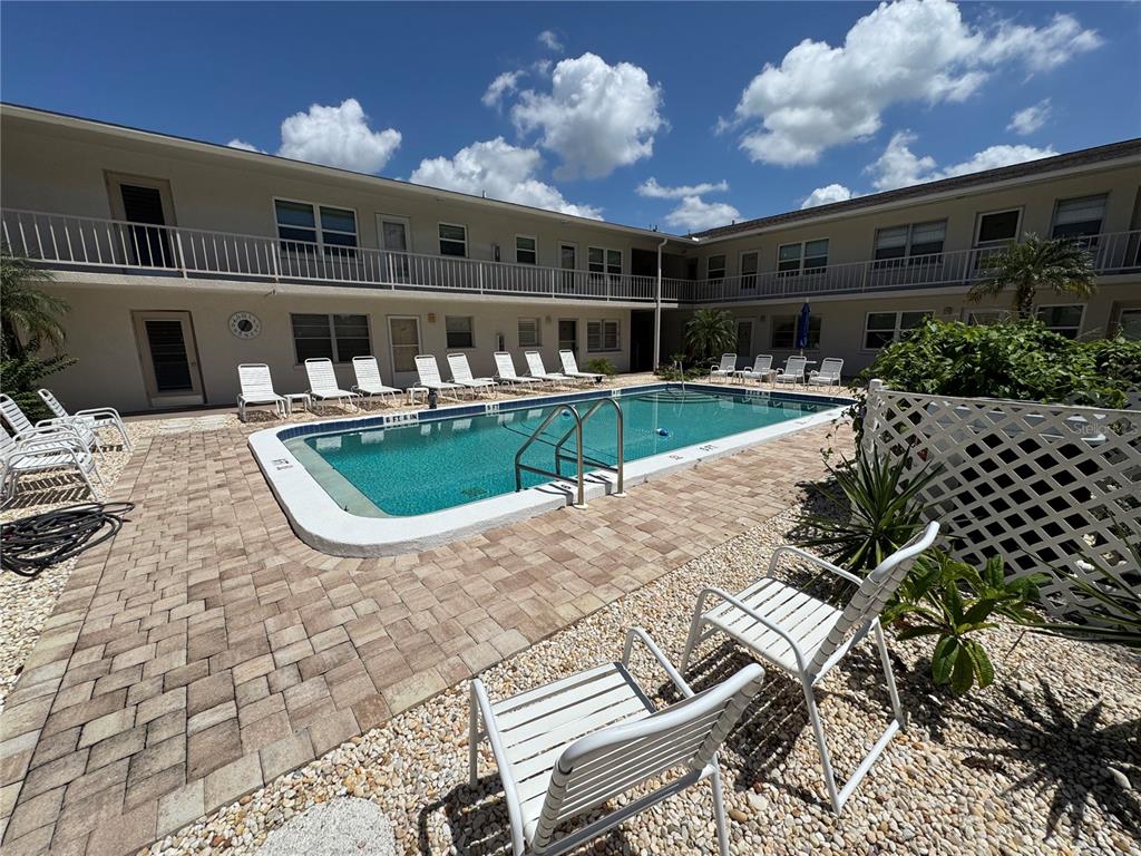 A swimming pool sits in the center of a courtyard surrounded by a two-story apartment building — 510 GRANADA AVENUE UNIT 105, VENICE, FL