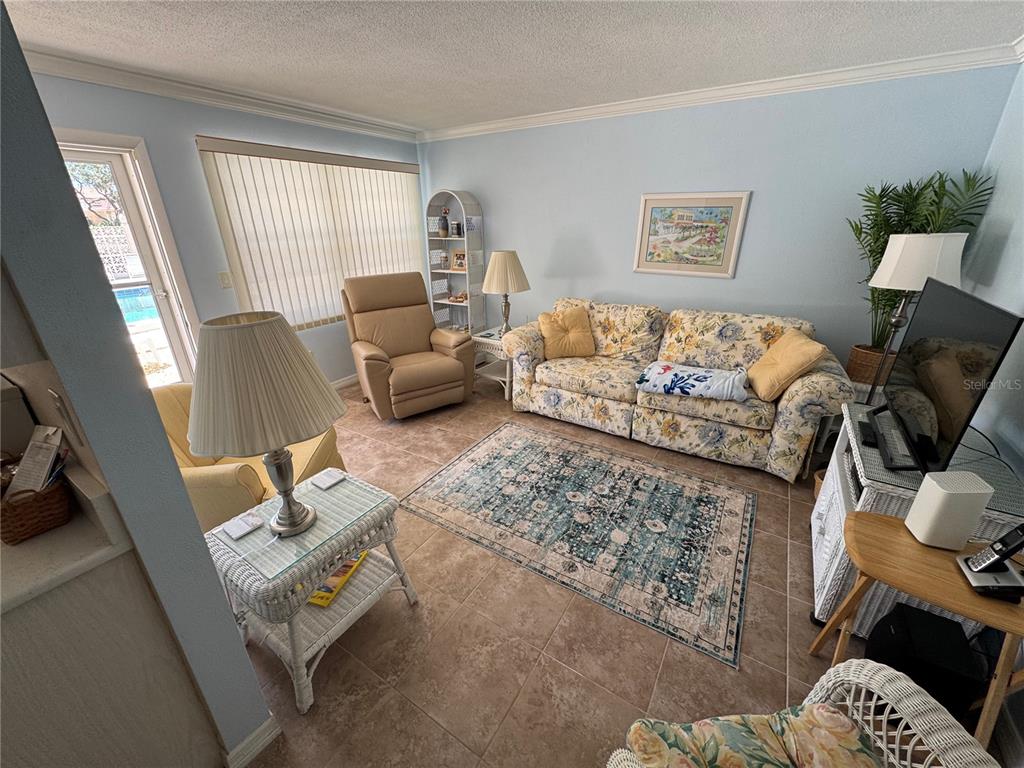 A living room features a floral sofa, a recliner, tile flooring, and a patterned area rug — 510 GRANADA AVENUE UNIT 105, VENICE, FL