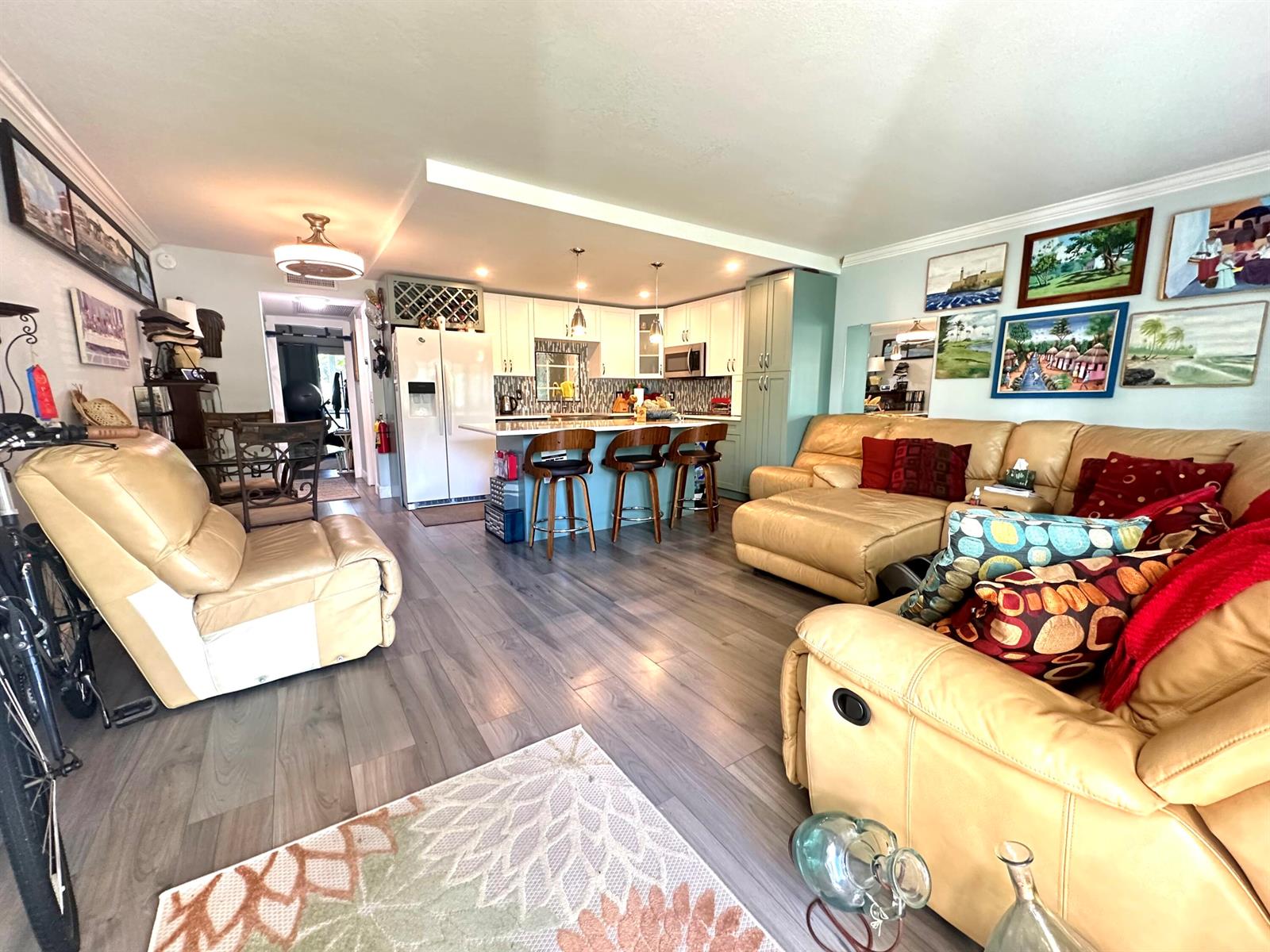An open-concept living room and kitchen featuring light wood flooring and tan leather furniture — 1092 Newport S # 1092, Deerfield Beach FL 33442, DEERFIELD BEACH, FL