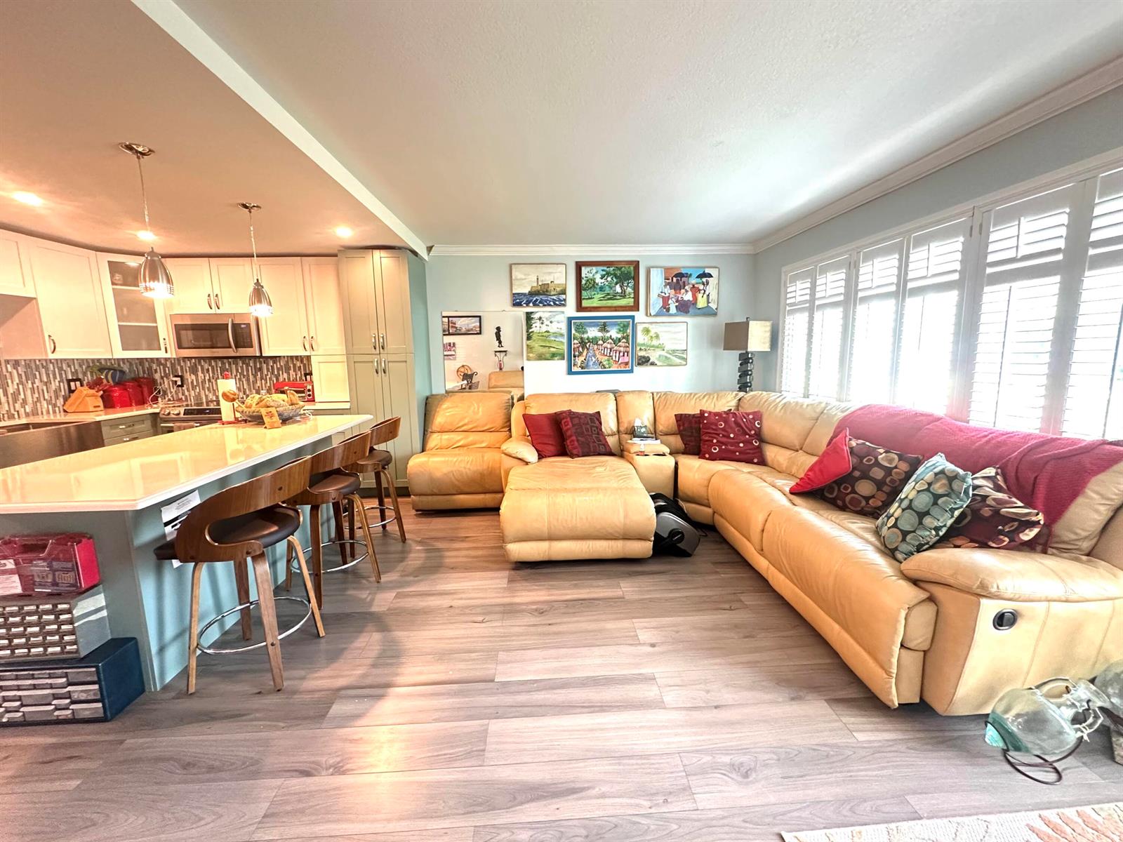 An open-concept kitchen with a breakfast bar flows into a living room with leather seating — 1092 Newport S # 1092, Deerfield Beach FL 33442, DEERFIELD BEACH, FL