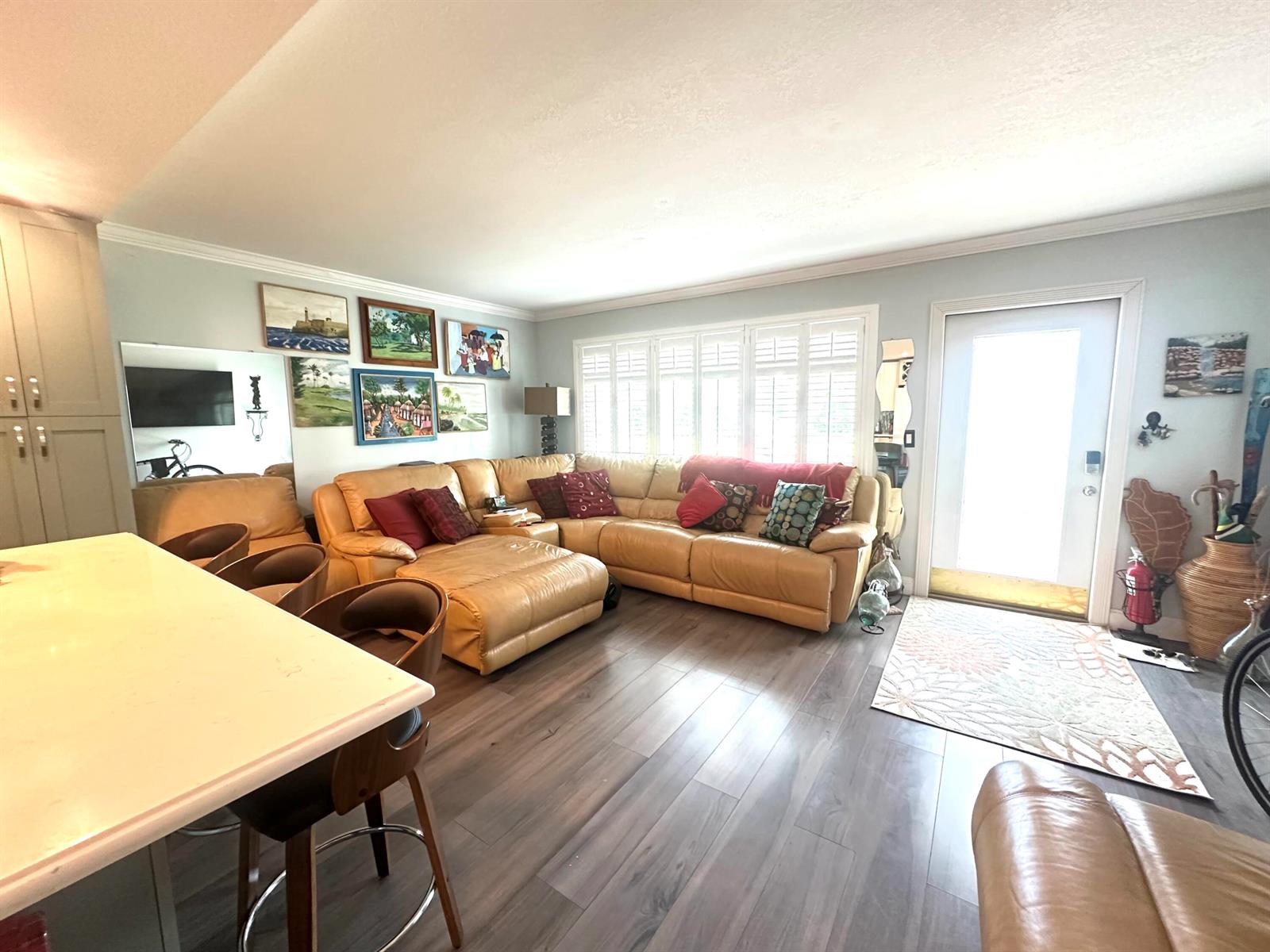 A living room features a tan leather sectional, wood flooring, and a white kitchen island — 1092 Newport S # 1092, Deerfield Beach FL 33442, DEERFIELD BEACH, FL