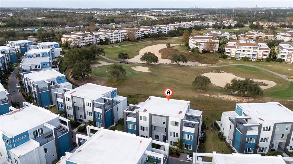 An aerial view shows a multi-story apartment complex overlooking a golf course — 7740 SANDY RIDGE DRIVE UNIT 131, REUNION, FL
