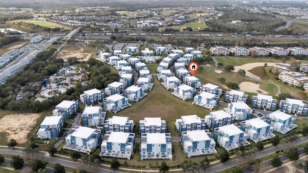An aerial view shows a residential complex of multi-story townhomes surrounding a central green space — 7740 SANDY RIDGE DRIVE UNIT 131, REUNION, FL