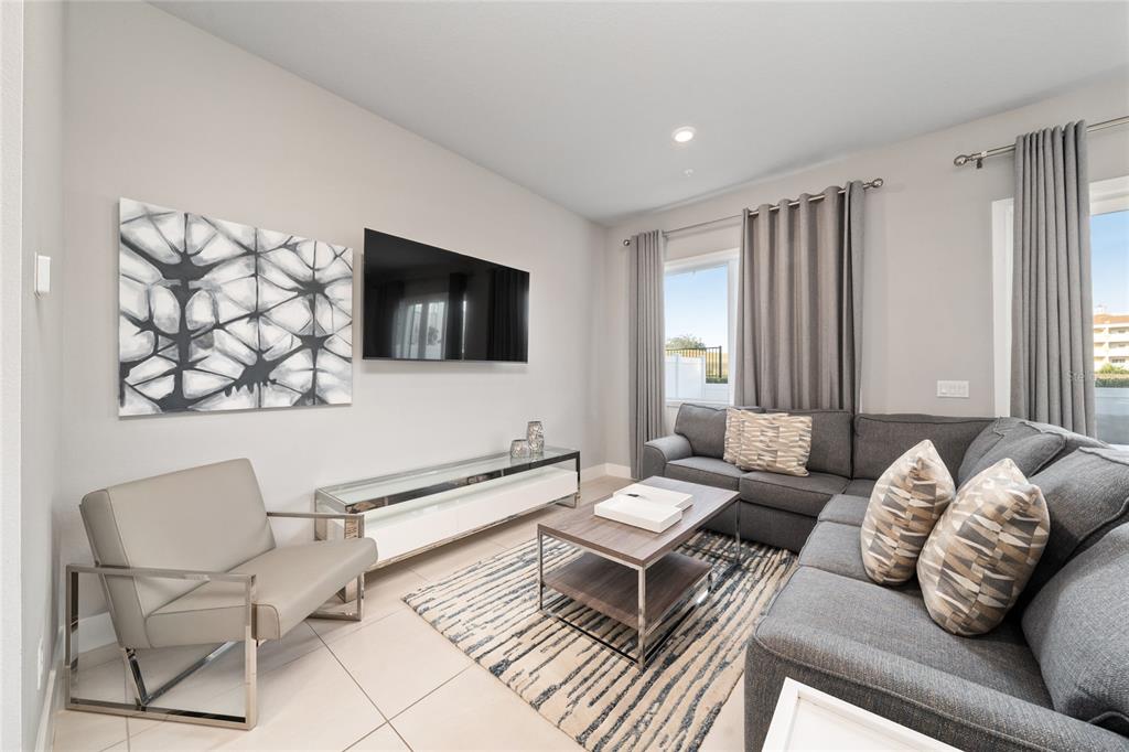 A living room features a gray sectional sofa, a television, and a modern coffee table — 7740 SANDY RIDGE DRIVE UNIT 131, REUNION, FL