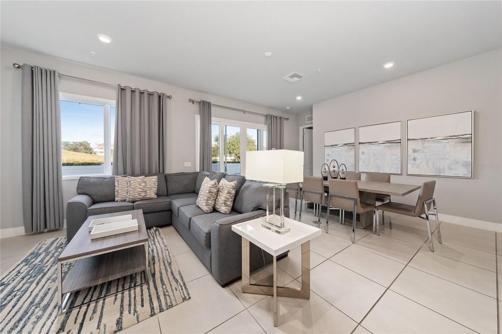 A living and dining area features a gray sectional sofa, dining table, and tile flooring — 7740 SANDY RIDGE DRIVE UNIT 131, REUNION, FL