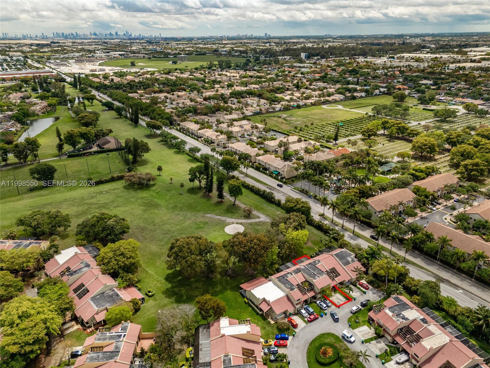 An aerial view shows a residential neighborhood with townhomes, green spaces, and a nearby road — 3325 Torremolinos Ave # 44, Doral FL 33178, DORAL, FL