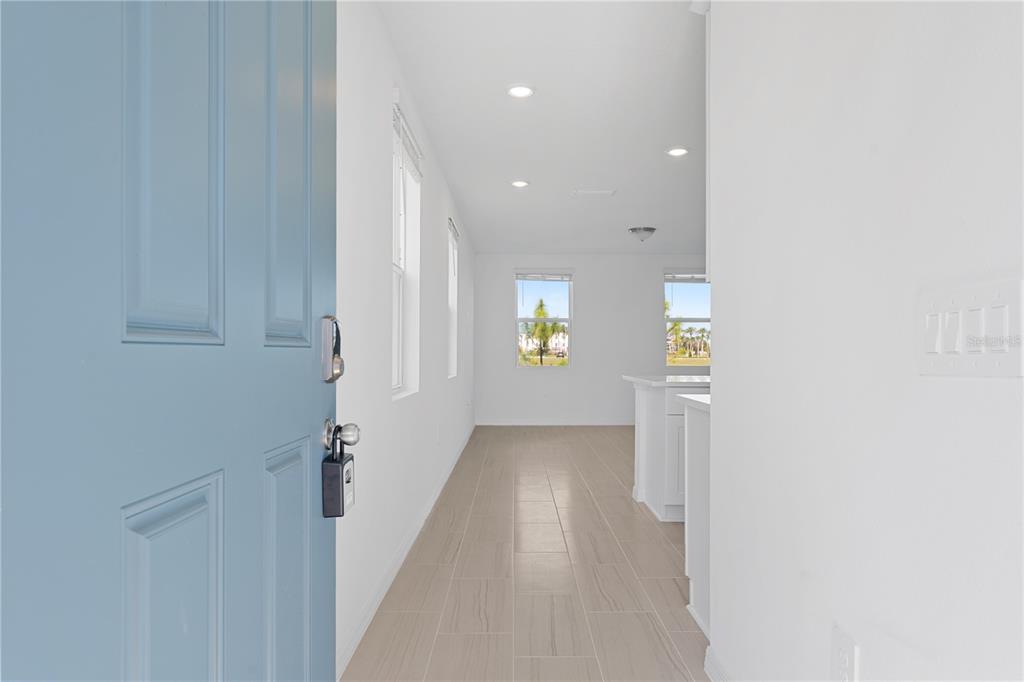 A view from an open blue front door into a hallway with tile flooring — 16452 HAPPY EAGLE DRIVE, CLERMONT, FL