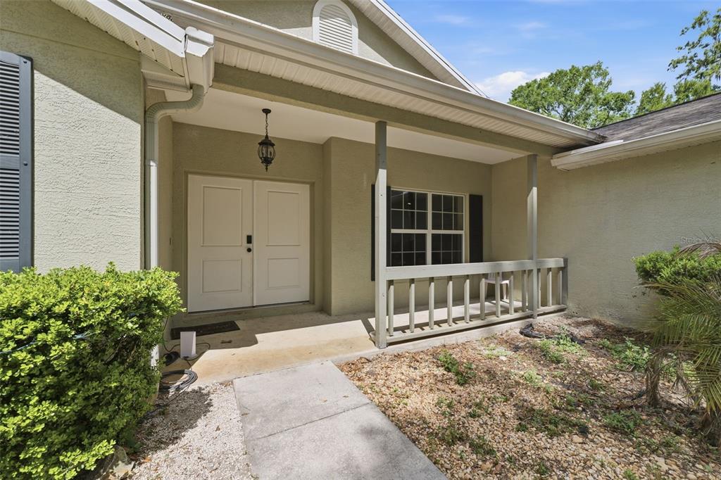 A front porch with a concrete walkway, double doors, and a wooden railing — 11459 TRAIL RIDGE RUN, BROOKSVILLE, FL